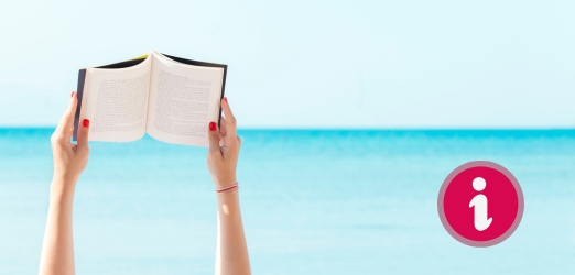 Frauenhände in der Luft, halten ein aufgeschlagenes Buch, im Hintergrund Meer